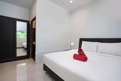 a bedroom with a bed with a red pillow on it at Family 2BR Villa Lancelot 3 with Jacuzzi Pool, just 10 min drive NaiHarn and Rawai in Rawai Beach