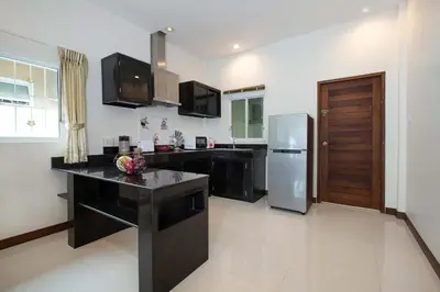 a kitchen with a refrigerator and a counter top at Family 2BR Villa Lancelot 3 with Jacuzzi Pool, just 10 min drive NaiHarn and Rawai in Rawai Beach