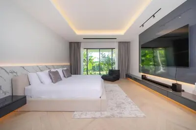 a bedroom with a white bed and a flat screen tv at Elite Villa Patong Phuket in Patong Beach