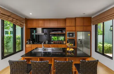 a kitchen with wooden cabinets and stainless steel appliances at Villa Fam with Private Pool Near Nai Harn Beach in Rawai Beach