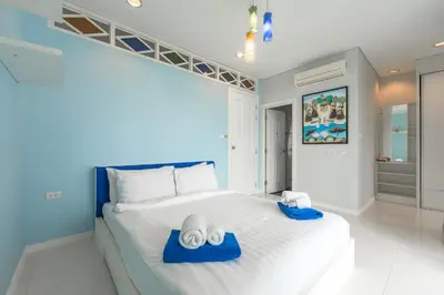 a bedroom with a large white bed with blue accents at C205 4BR Pool, Mountain Views & Prime Location in Kamala Beach