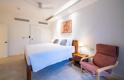 a bedroom with a white bed and a chair at JSD Prime Property-Cherngtalay in Laguna Phuket