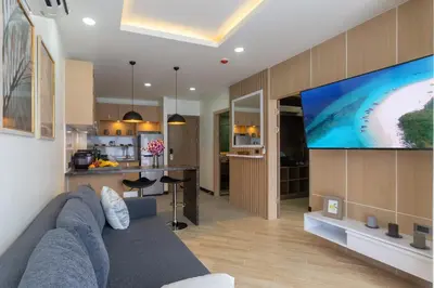 a living room with a blue couch and a large screen tv at Calipso Garden 108 in Rawai Beach
