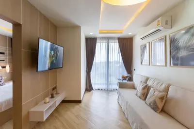 a living room with a couch and a tv on a wall at Calipso Garden 304 in Rawai Beach