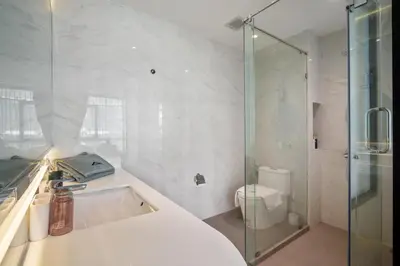 a white bathroom with a shower and a toilet at Pool View 1310 Wyndham Condo in Nai Thon Beach