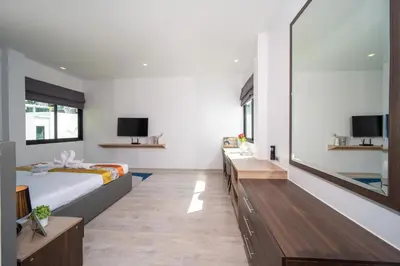 a bedroom with a bed and a tv and a mirror at \u4e5d\u96c5\u96c6 The Nine Refined Retreats in Rawai Beach