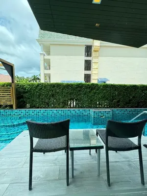 two chairs and a glass table next to a pool at Beachfront Family Pool 1 BR 1 Living Patong Phuket in Patong Beach