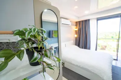 a hotel room with a mirror and a plant at White Room in Ban Mai Salae