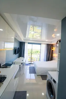 a kitchen and a bedroom with a bed and a window at White Room in Ban Mai Salae