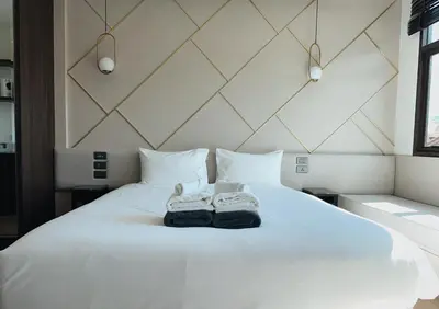 a bedroom with a white bed with shoes on it at Praud Karon in Karon Beach