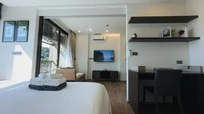 a hotel room with a bed and a desk and a room at Praud Karon in Karon Beach