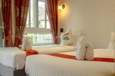 a hotel room with two beds with towels on them at The Golden Beach Resort Naiyang in Nai Yang Beach