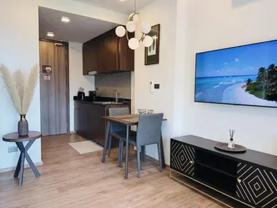 a kitchen and dining room with a table and a television on the wall at Praud Karon 605 in Karon Beach