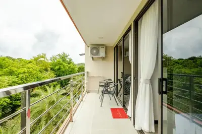 a balcony of a house with a view of trees at Room 303 Rawai Beach Condo in Nai Harn Beach