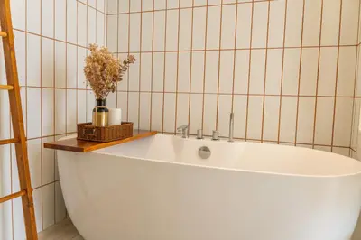 a white tub in a bathroom with a vase of flowers at \u4e91\u6816\u522b\u9662 Cloudrest Villa in Phuket Town