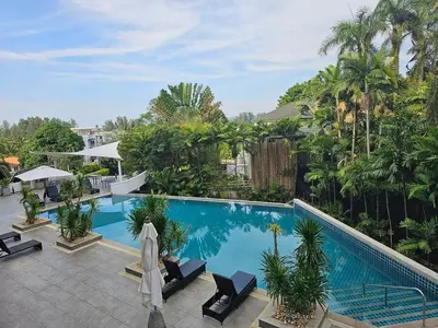 a large swimming pool with palm trees and a resort at Stylish 2-Bedroom Apartment with Pool Access in Surin Beach
