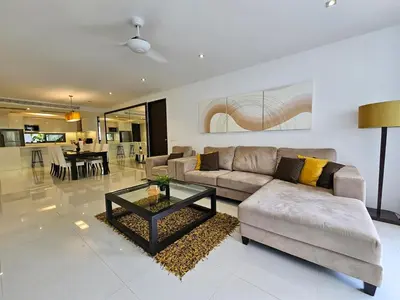 a living room with a couch and a table at Stylish 2-Bedroom Apartment with Pool Access in Surin Beach