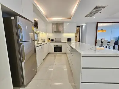 a kitchen with white cabinets and a stainless steel refrigerator at Stylish 2-Bedroom Apartment with Pool Access in Surin Beach