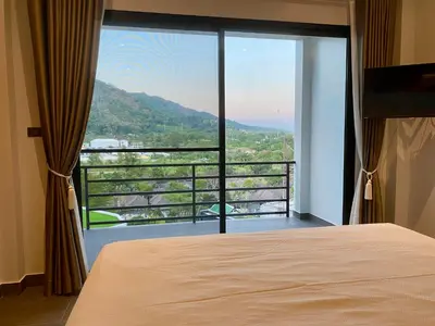a bedroom with a bed and a large glass window at Viewpoint Villa with Private Infinity Pool - 2BR in Rawai Beach