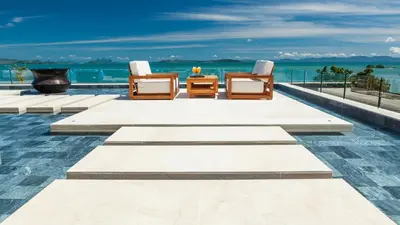a pool with two chairs and a table and the ocean at Villa Amarapura in Ko Lek