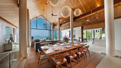 a dining room with a long table and chairs at Villa Amarapura in Ko Lek