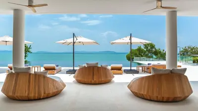 a room with chairs and umbrellas and the ocean at Villa Amarapura in Ko Lek