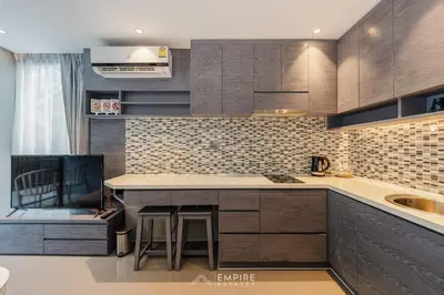 a kitchen with brown cabinets and a counter top at CityGate Kamala 1BR 3 min Beach in Kamala Beach