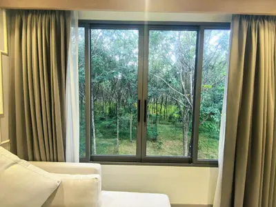 a bedroom with a window with a view of trees at \u7af9\u5149\u522b\u9662 Bamboo Radiance Villa in Ban Thalat Choeng Thale