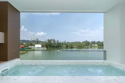 a large swimming pool with a view of a lake at Angsana Oceanview Residence Luxurious 2BR Lakeview Apartment in Laguna Phuket