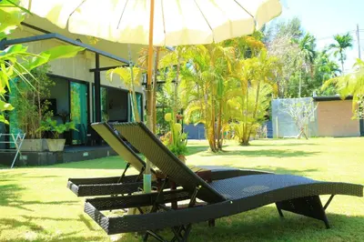 a couple of lawn chairs sitting under an umbrella at Baan Norkna Bangtao in Bang Tao Beach