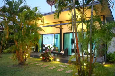 a house with palm trees in front of it at Baan Norkna Bangtao in Bang Tao Beach