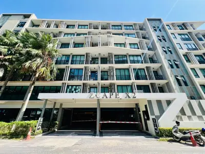 a large building with a palm tree in front of it at Zcape 2 Phuket by RESAVA in Bang Tao Beach