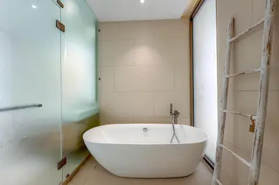 a bath tub in a bathroom with a glass door at New Tropical Modernity! 3BR Pool Villa LuxPride4 L21 near Laguna Phuket in Bang Tao Beach