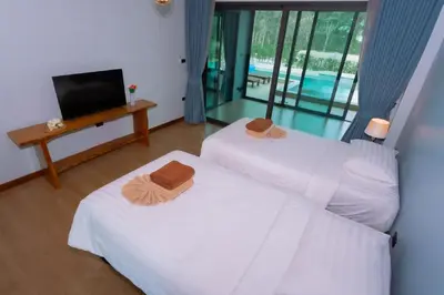 two beds in a room with a tv and a television at Seashine Private Pool Villa at Klong Muang in Klong Muang Beach