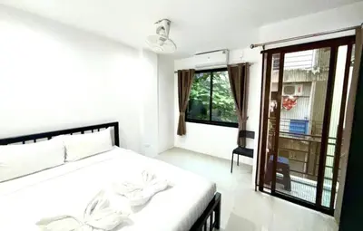 a white bedroom with a bed and a window at Patong Easy Life 3 in Patong Beach