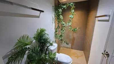 a bathroom with a toilet with plants on the wall at C212 Relaxing Condo Rooftop Pool & Ocean Views in Chalong