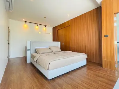a bedroom with a large white bed and wooden walls at Modern ZEN Vibe 3BR Pool Villa Phuket in Ban Tha Khreng