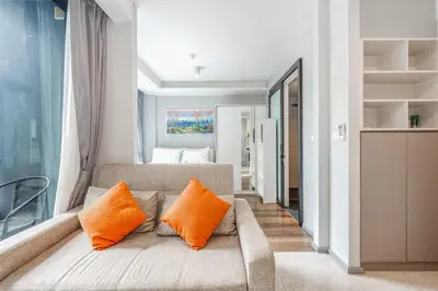 a living room with a couch with two orange pillows at C209 Surin Beachside Sun Escape & Infinity Pool in Surin Beach