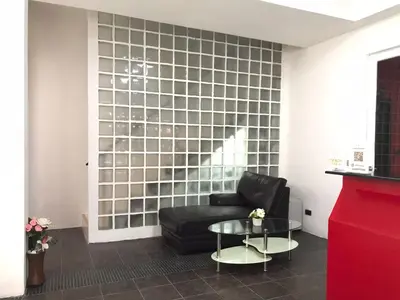 a living room with a black couch and a glass table at Patong Central Budget Stay in Patong Beach