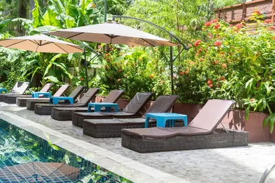 a row of lounge chairs and umbrellas next to a pool at Patong Central Budget Stay in Patong Beach