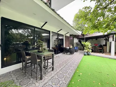 a patio with a table and chairs and a green lawn at Rawai House 16 in Ban Saiyuan (1)
