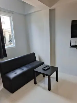 a living room with a black couch and a table at GN House Bangtao in Ban Thalat Choeng Thale