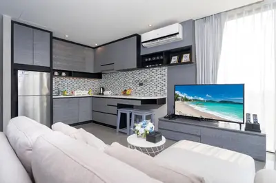 a living room with a white couch and a tv at Tropics Kamala Hill View Suite CTG L605, near Kamala Beach and Fantasea in Kamala Beach