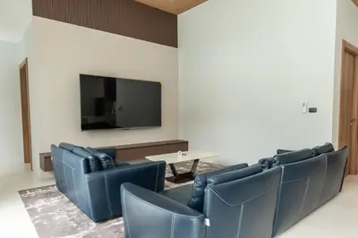 a waiting room with blue chairs and a table and a tv at Mouana Breeze Mai Khao 4-bedroom Pool Villa 9919 in Mai Khao Beach