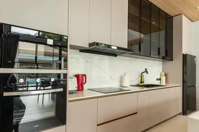 a kitchen with white cabinets and black appliances at Mouana Breeze Mai Khao 4-bedroom Pool Villa 9919 in Mai Khao Beach