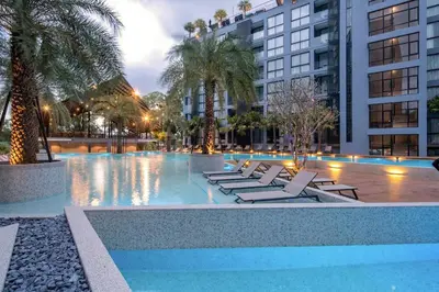 a swimming pool with lounge chairs and palm trees at Tropics Kamala Apartment CTG L606, Several Pools, Gym & Rooftop in Kamala Beach