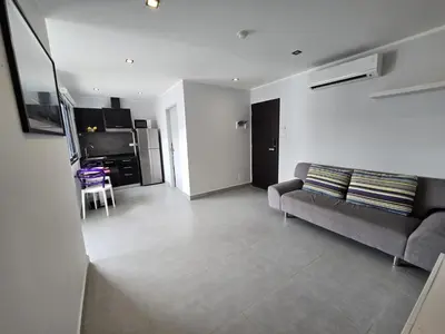 a living room with a couch and a kitchen at Sleek Corner 1 Bed Apt T1-607 in Chalong