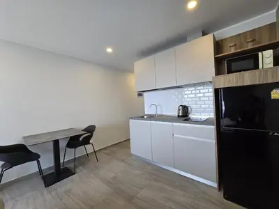 a kitchen with a table and a black refrigerator at Modern Studio Apt T3-526 in Chalong