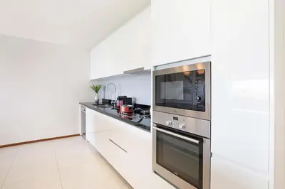 a white kitchen with a microwave and a stove at Stunning Seaview Escape - Modern and Elegant in Kata Beach