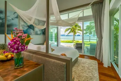 a bedroom with a bed and a vase of flowers on a table at Baan Klong II in Ko Yao Noi